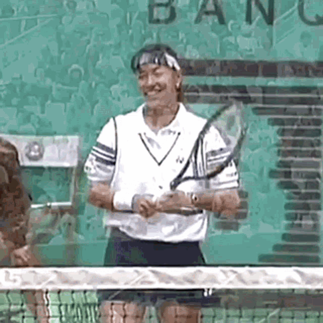 a tennis player is smiling while holding a tennis racquet