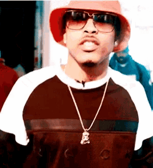 a man wearing a red hat and sunglasses is wearing a necklace with a bear on it