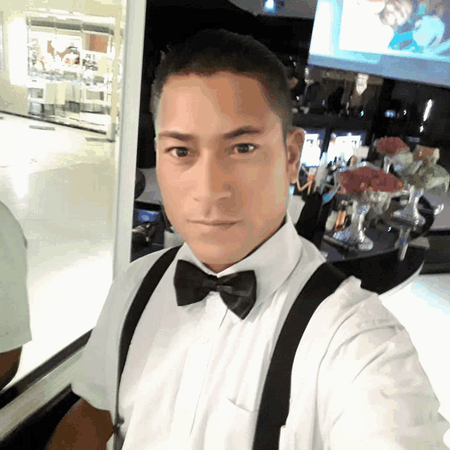 a man wearing a bow tie and suspenders takes a picture of himself