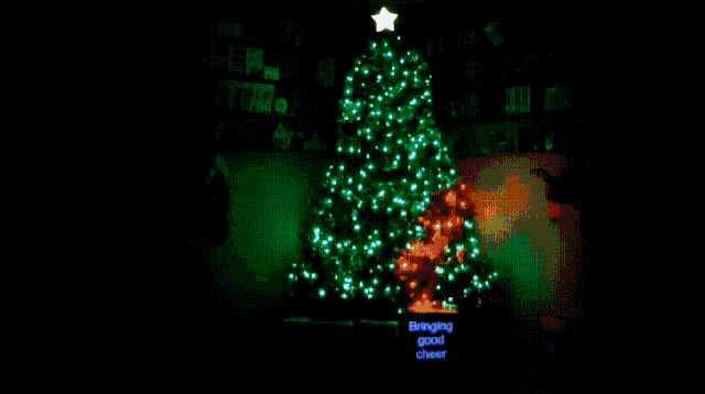 a christmas tree is lit up in a dark room with a star on top
