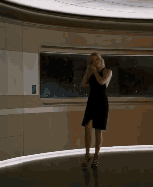 a woman in a black dress is dancing in a room