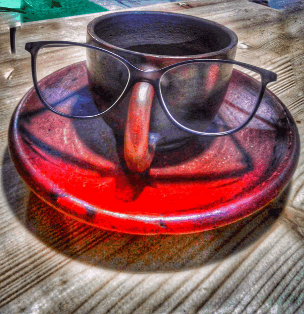 a pair of glasses sitting on top of a red saucer