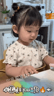 a little girl is sitting at a table with foreign writing on the bottom