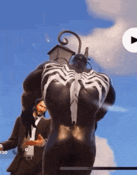 a man in a suit standing next to a statue of venom .