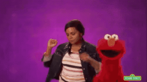 a woman is dancing in front of elmo from sesame street .