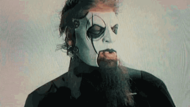 a man with a beard and a mask on his face looks at the camera