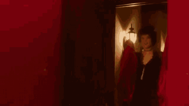 a woman in a black dress is standing in a red room .