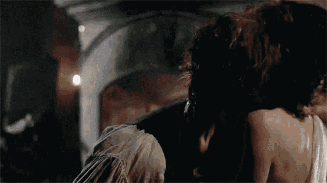 a man and woman are kissing in a dark room with a light behind them