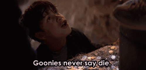 a young boy is standing in front of a pile of coins and says goonies never say die .