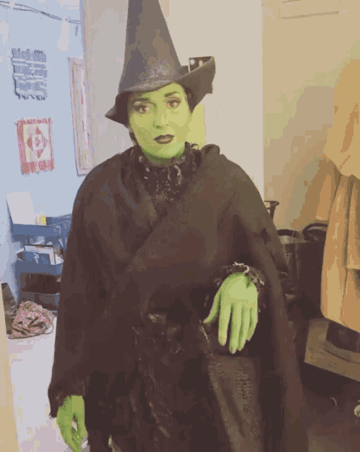 a woman in a green witch costume is standing in a hallway