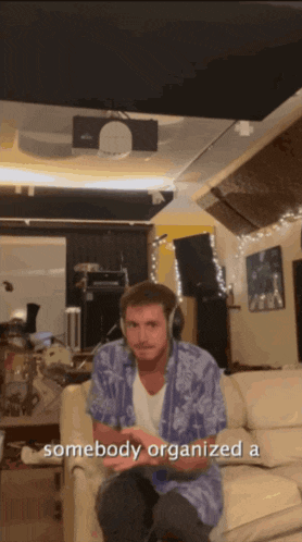 a man wearing headphones sits on a couch in a room with the words somebody organized a below him