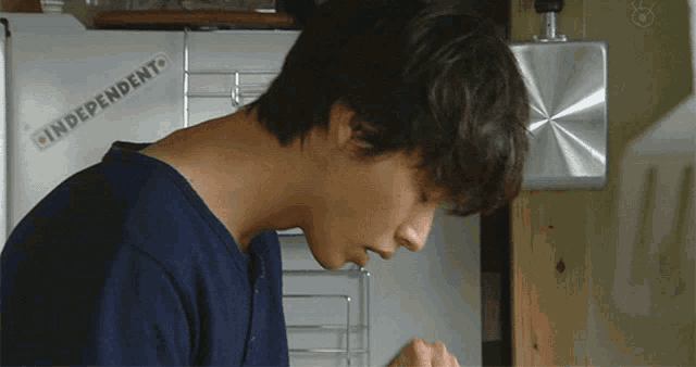 a man in a blue shirt is standing in front of a refrigerator that says independent