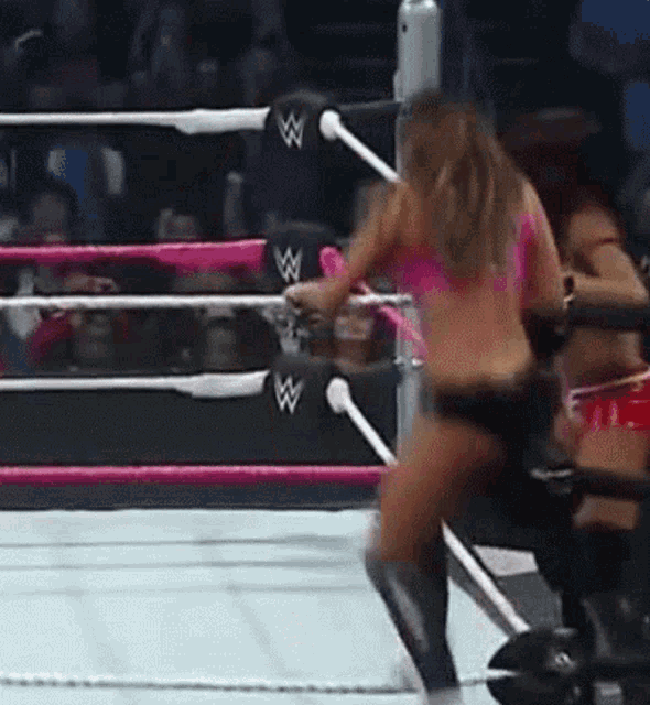 a woman is standing in a wrestling ring with a crowd watching her .