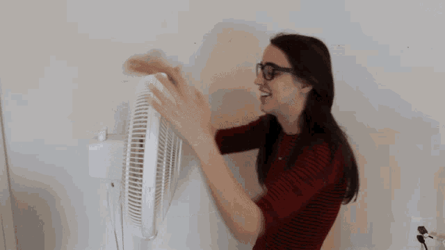 a woman wearing glasses holds a white fan in her hands