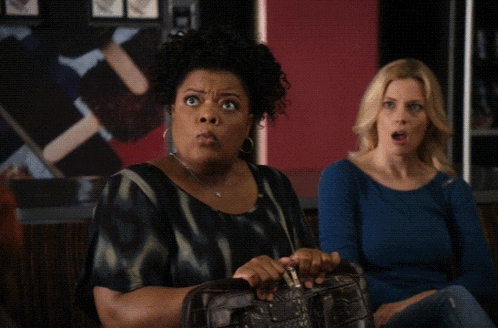 a woman with a surprised look on her face is holding a purse next to another woman who says what ?