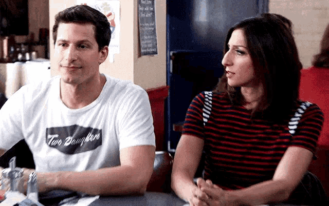 a man and a woman are sitting at a table looking at each other .