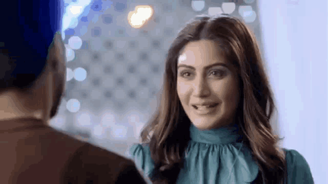 a woman in a blue dress is smiling and looking at a man .