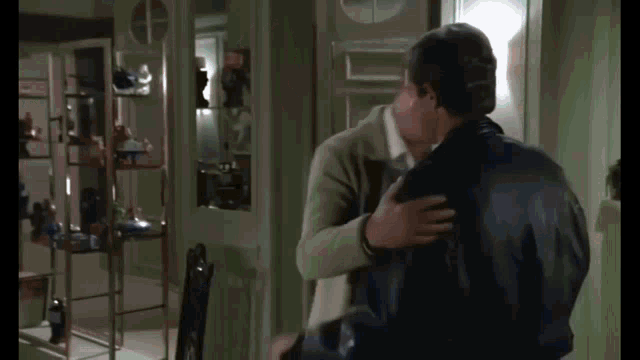 two men are hugging each other in a living room