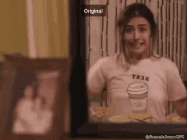 a woman wearing a t238 t-shirt is smiling and looking out a window
