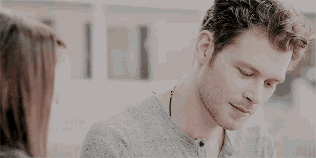 a man in a grey shirt looks down at something