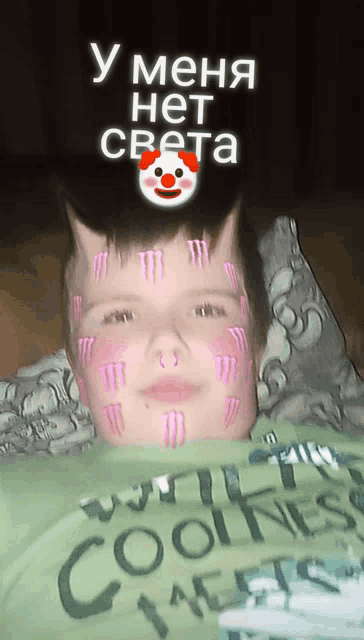 a boy with monster energy drinks on his face is wearing a green shirt that says coolness
