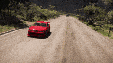 a red car is driving down a road