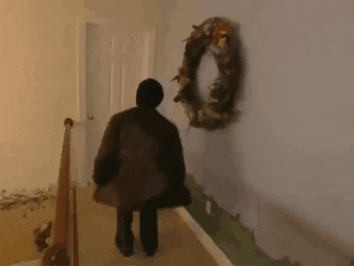 a person walking down a hallway with a wreath hanging on the wall