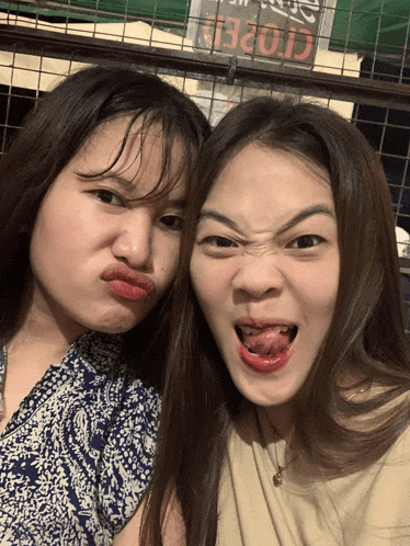 two girls are making funny faces in front of a closed sign