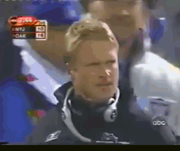 a man wearing headphones looks at the camera with a scoreboard in the background that says kentucky 50 oak 26