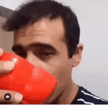 a man is drinking from a red cup with a sound button on it .