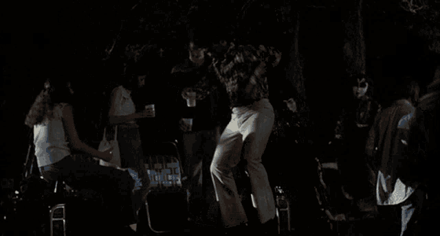 a man in a camo shirt is dancing in front of a crowd