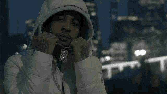 a man wearing a white jacket with a hood and a necklace that says ' i love you '