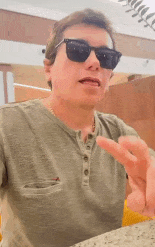 a man wearing sunglasses and a green shirt is pointing