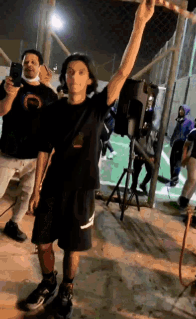a man in a black shirt is standing in front of a speaker and holding a hula hoop .