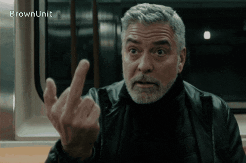 a man with gray hair and a beard is giving the middle finger in front of a sign that says brown unit