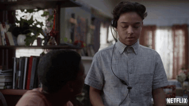 a man wearing headphones talks to another man with a netflix logo in the background