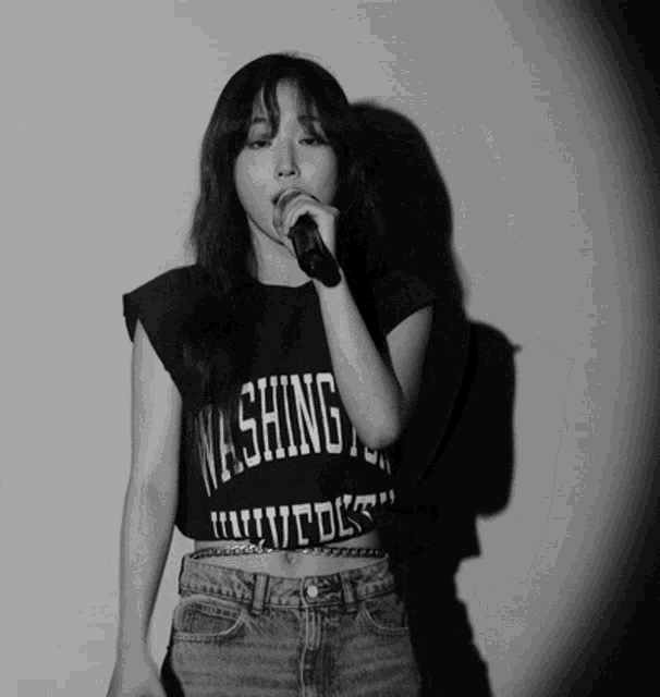 a woman singing into a microphone wearing a shirt that says washington