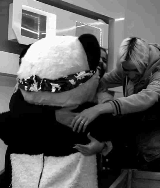 a black and white photo of a person holding a stuffed panda bear