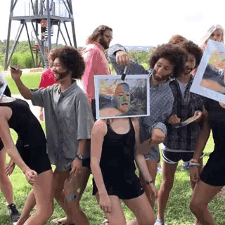 a group of people are posing for a picture while holding paintings in front of their faces
