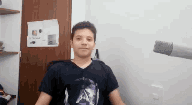 a young boy sitting in front of a microphone in a room with a sign on the wall that says ' cocinar '