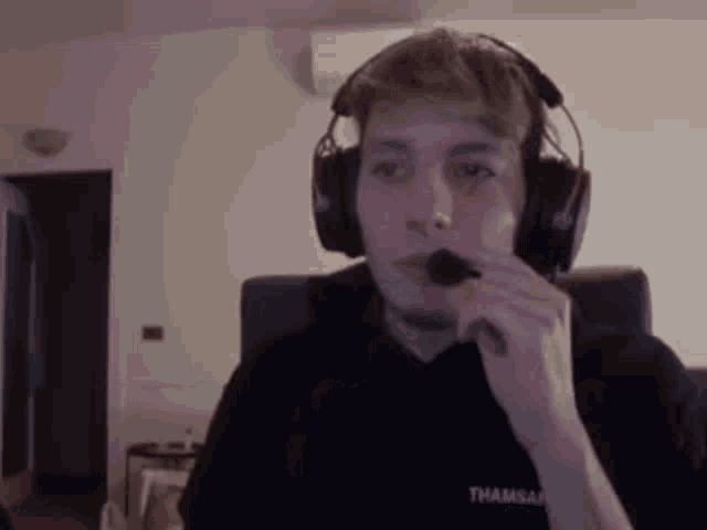 a man wearing headphones and a microphone is sitting in front of a computer .