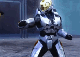 a man in a silver armor with a yellow helmet is standing in the snow .