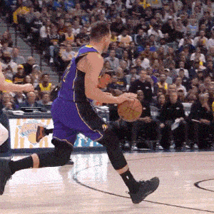 a basketball player in a purple and black uniform is dribbling a basketball