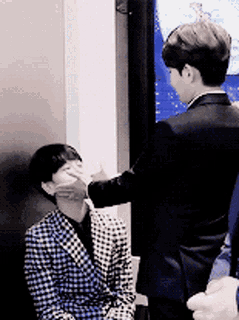 a man in a suit covering another man 's face with his hand