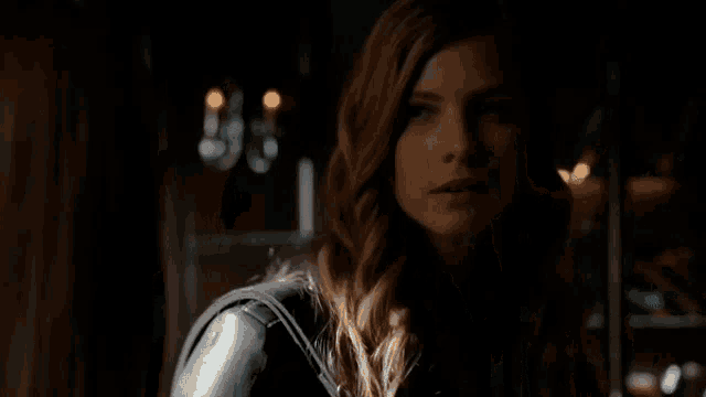 a woman in a black leather jacket is standing in the dark