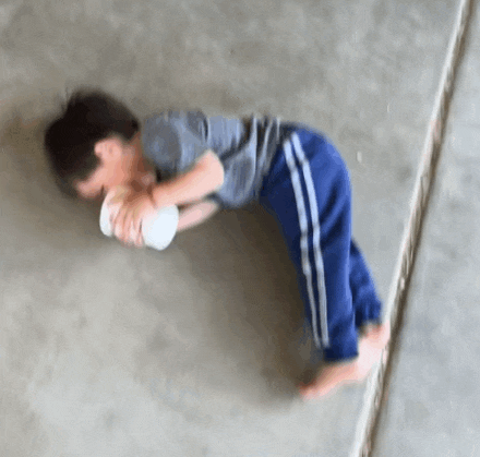 a young boy is laying on the floor holding a white object