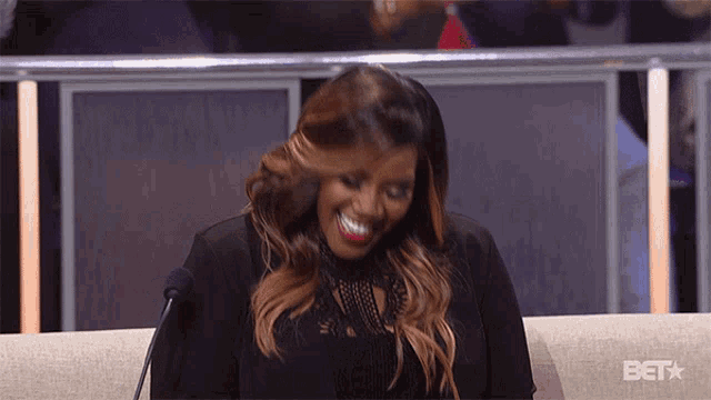 a woman is sitting on a couch with a bet logo in the background