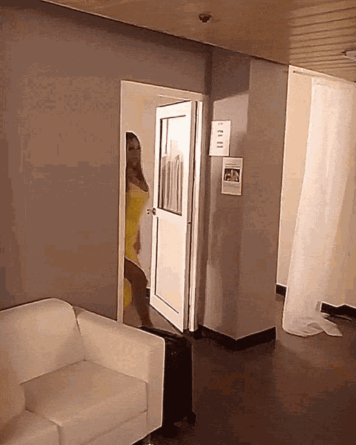 a woman in a yellow dress is standing in a room with a sign on the wall that says ' exit '