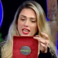 a woman is holding a red book in her hand and looking at it .
