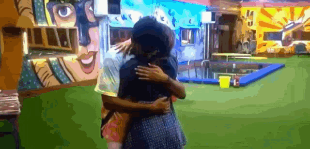 a man and a woman hugging in front of a colorful wall .